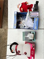 Overview showing Santa figure, boxed acrylic trees, boxed angel topper, boxed church figurine, light-up snowman