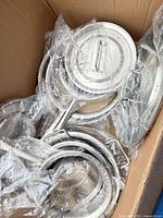 Box containing multiple stainless steel pots and lids in plastic