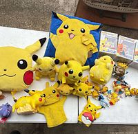 Overview of entire lot: plush pillows, multiple Pikachu plush, hand puppet, Funko Pop boxes, mini figures