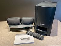 Entire system showing console, two speakers, subwoofer, remote, manual