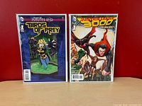 Front view of both bagged comics upright against red wall