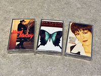 Front view of three sealed cassette tapes showing album artwork