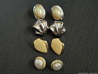 Front view showing three of the four earring pairs: silver shell drop, gold geometric studs, gold pearl rhinestone studs