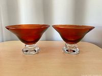 Front view of both cranberry flash glass pedestal bowls on table