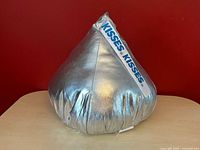 Front view of silver Hershey’s Kisses plush pillow on table