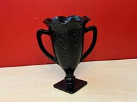 Front view showing raised classical motif, handles, pedestal base