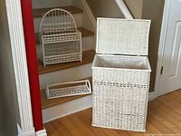 All three white wicker pieces grouped: hamper, shelf, towel rack