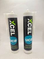 Front view showing two sealed Xcel UCB adhesive cartridges with nozzles