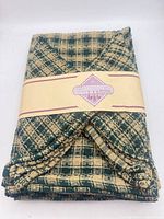 Front of bundled cotton kitchen linens showing plaid pattern and branded paper band