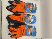 Three pairs orange and black gloves with packaging