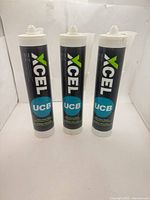 Three Xcel UCB adhesive tubes standing