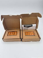 Two open Amazon cardboard boxes each containing eight orange Amazon Basics AAA batteries