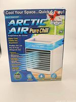 Front of boxed Arctic Air Pure Chill evaporative air cooler showing product image and key features