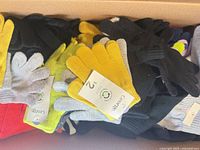 Box containing multiple pairs of knit gloves showing tags and colours