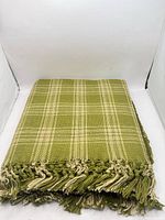 folded green plaid throw showing overall pattern and fringe