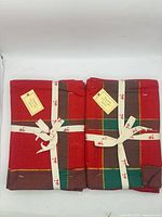 Two ribbon-tied bundles of red plaid napkins side by side