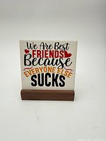 Front view of ceramic plaque in wooden stand showing text and design