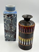 Blue and white Royal Copenhagen square vase next to brown Italian cylindrical vase