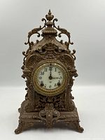 Frontal view of ornate bronze mantel clock showing dial and case details