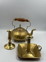 Group view of kettle, tall candlestick and square chamberstick