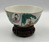 Front view of bowl on carved stand showing painted figures and foliage