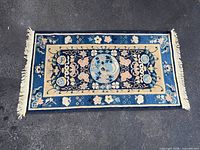 Full view of blue floral hand knotted rug with fringe
