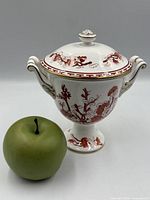 Covered vase beside apple for scale