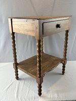 Full view of wooden two-tier table showing top, drawer, legs and shelf