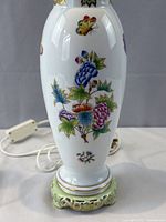 Close view of porcelain body showing floral and butterfly decoration and pierced green foot