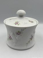 Angled view of dish with lid on showing relief and painted flowers