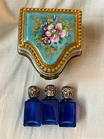 Closed porcelain box and three bottles displayed