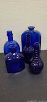 Four cobalt blue glass bottles grouped together showing shapes and sizes