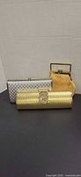 Front view of all three clutches: gold cylindrical, silver rectangular, gold pleated frame bag