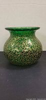 Front view of emerald green glass vase showing shape and gold enamel pattern