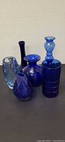 Group shot of all six blue glass vases