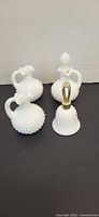 Four hobnail milk glass items: three cruets and one perfume bottle