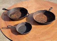 Three cast iron frying pans displayed top side up
