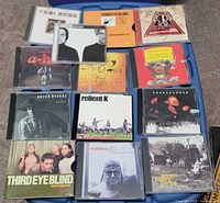 Overview of 12 CDs laid out on blue surface showing titles and artwork