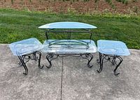 Full set of four wrought iron glass-top tables displayed outdoors