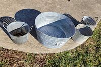 All four galvanized containers on concrete surface: wash tub, milk pail, two olive buckets