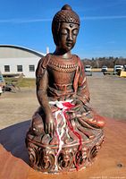 Front view of seated Buddha statue with wax drips