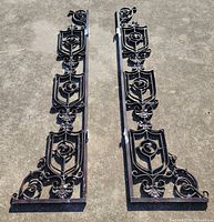 Full view of both ornamental iron gate brackets laid side-by-side
