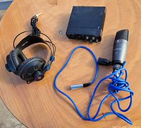Audio interface, microphone with cable and clip, headphones on tabletop