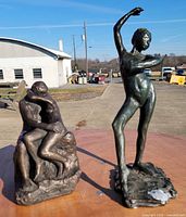 Front view of both resin statues on table outdoors