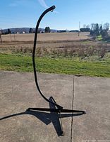 Full view of black metal arched hammock chair stand on concrete