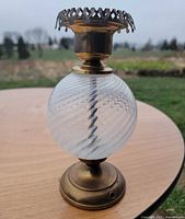 Full lamp showing brass base, clear glass font with white swirl, burner collar