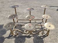Front view of wrought iron candelabra showing nine drip plates and scrolled feet