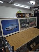 Three car posters displayed on table