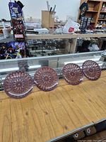 Four reverse-painted glass plates displayed on countertop