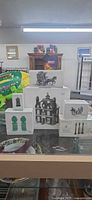 Stacked boxed Department 56 Dickens Village items on glass counter
